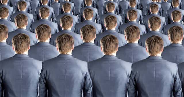 Large group of identical suit-wearing men seen from behind
