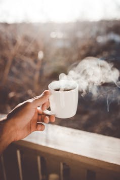 Hand holding steaming coffee mug
