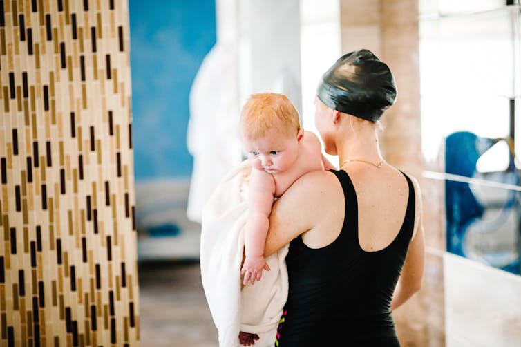 A woman holds a baby in a pool change room.