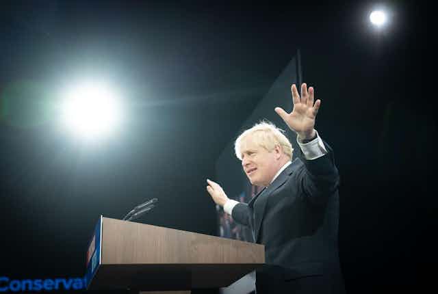 Boris Johnson raising his arms in the air as he delivers his party conference speech.