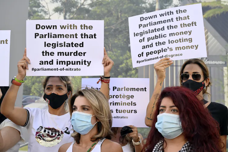Protesters wearng COVID masks hold up anti-government banners during a march in Beirut, September 2021.