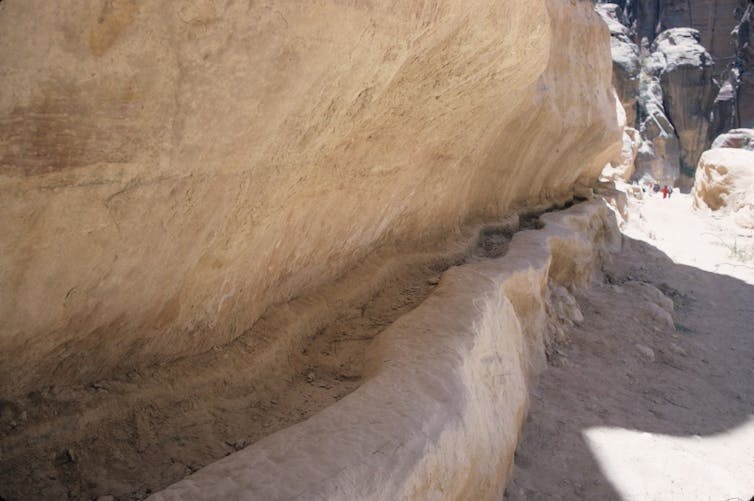 A trough carved out of a rock wall beside a path