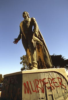 A statue of Christopher Columbus is vandalized with the word 'murderer' sprayed in red.