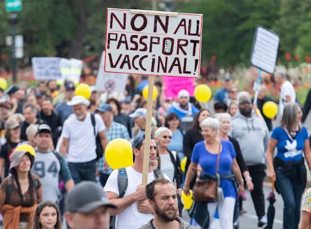 A crowd of protesters with a sign NON AU PASSPORT VACCINAL!