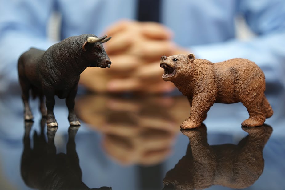 A model bull and bear on a table in front of a man in a shirt and tie