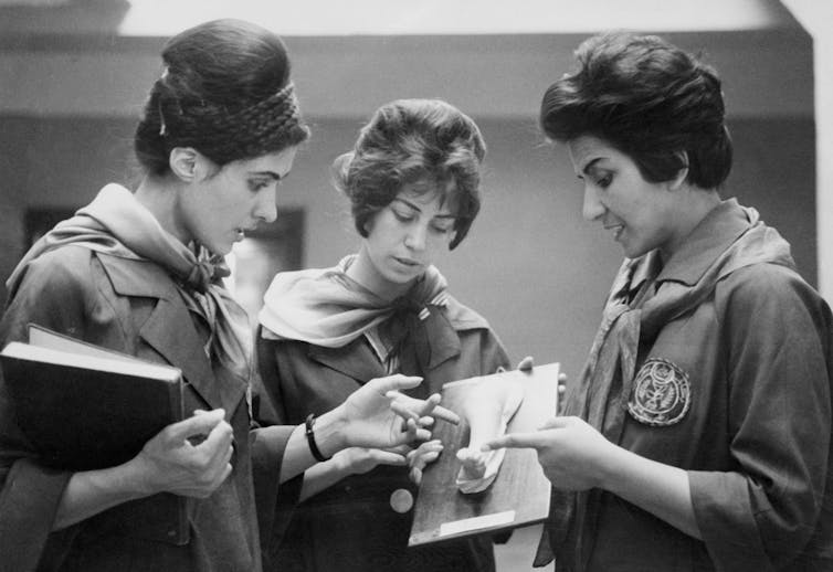 Two Afghan female medicine students examine a plaster model showing a part of a human body with the instructor.