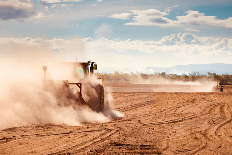 tractor ploughs dusty field