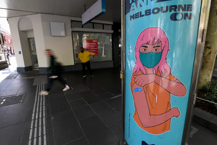 Billboard of cartoon woman with pink hair and bandaid after getting vaccinated.