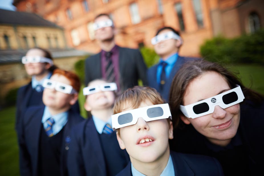 Teachers and pupils wear protective eyewear to observe an eclipse