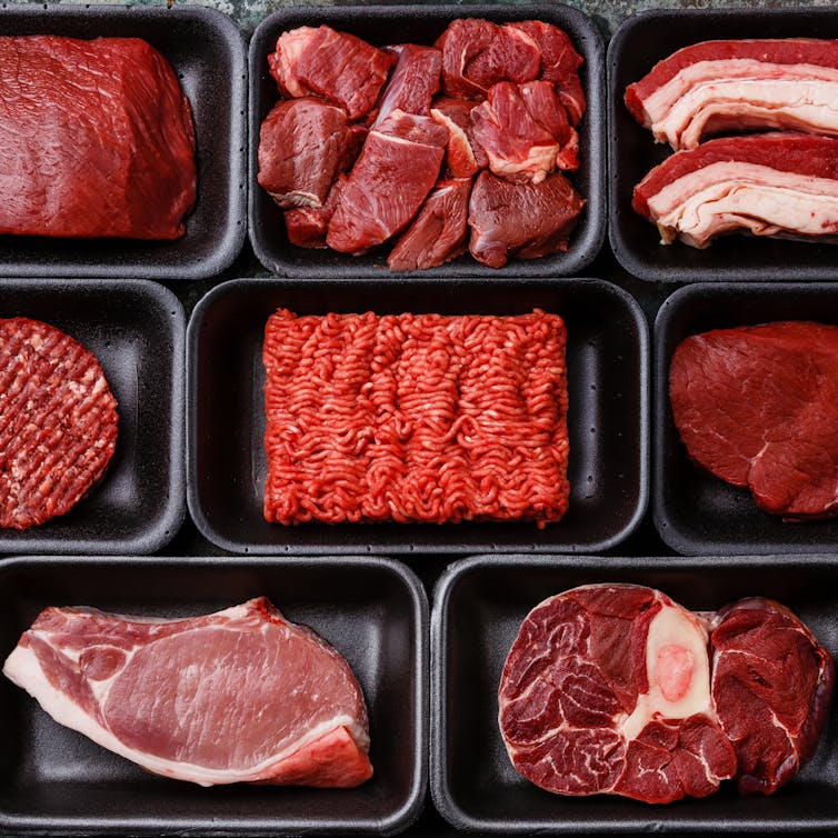 Black trays containing different types of red meat.