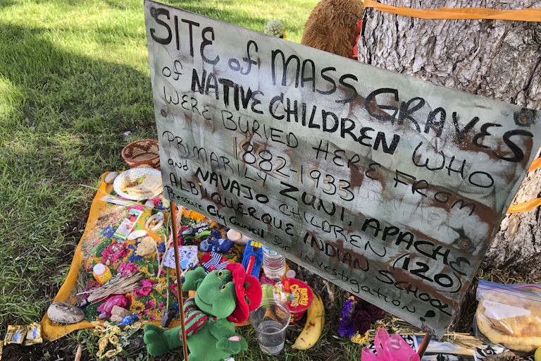 A sign saying "site of mass graves of Native children who were buried here from 1882 - 1933," in Albuquerque, New Mexico.