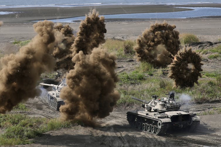 Los tanques atraviesan la playa rodeados de explosiones.