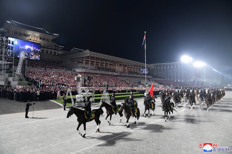 Soldiers on horseback parading in front of crowds in Pyongyang, North Korea