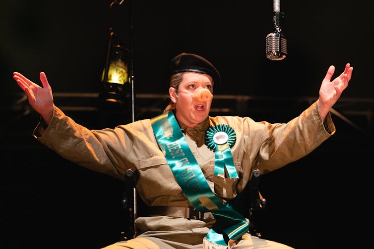 A woman in coveralls with a pig's nose.