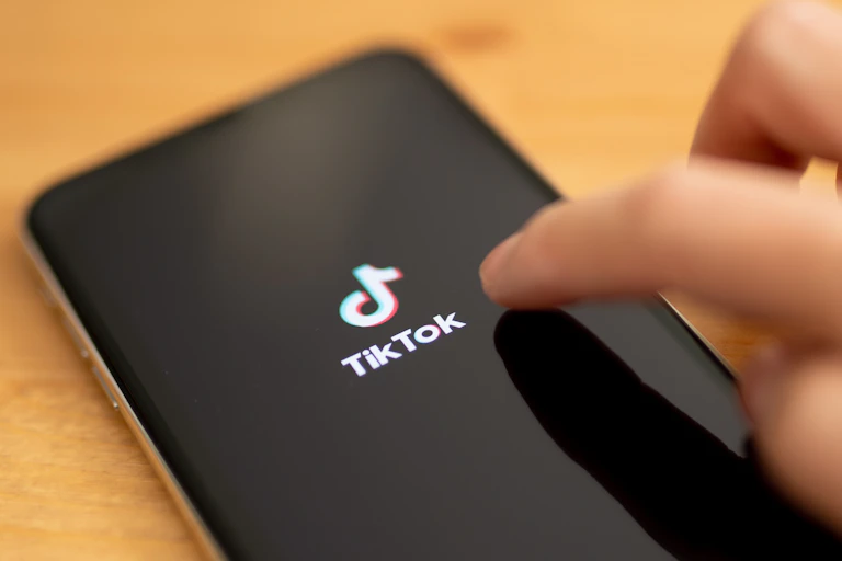 Hand touching a mobile phone screen with TikTok logo