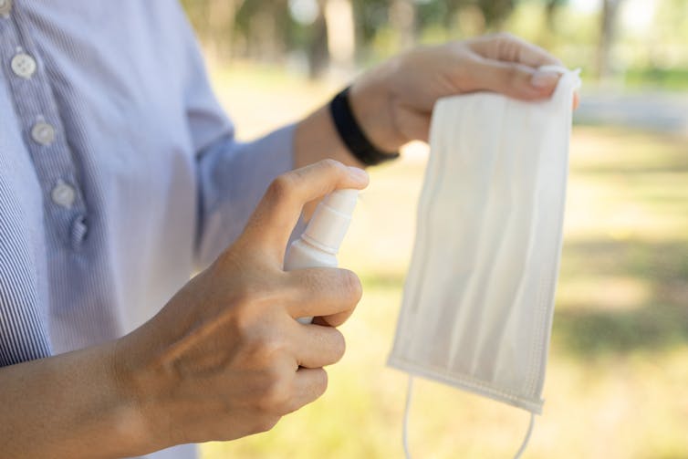 Person spraying disposable face mask