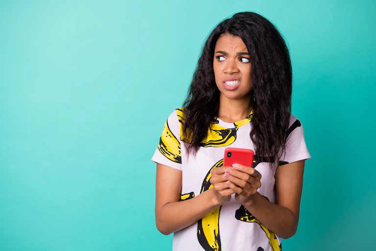 A woman looks disgusted while holding her phone.