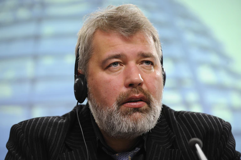 Shoulders-up photo of Dmitry Muratov wearing headphones and speaking into a microphone