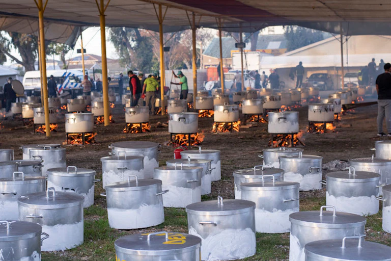 Volunteers attend to dozens of cooking pots at an open door kitchen