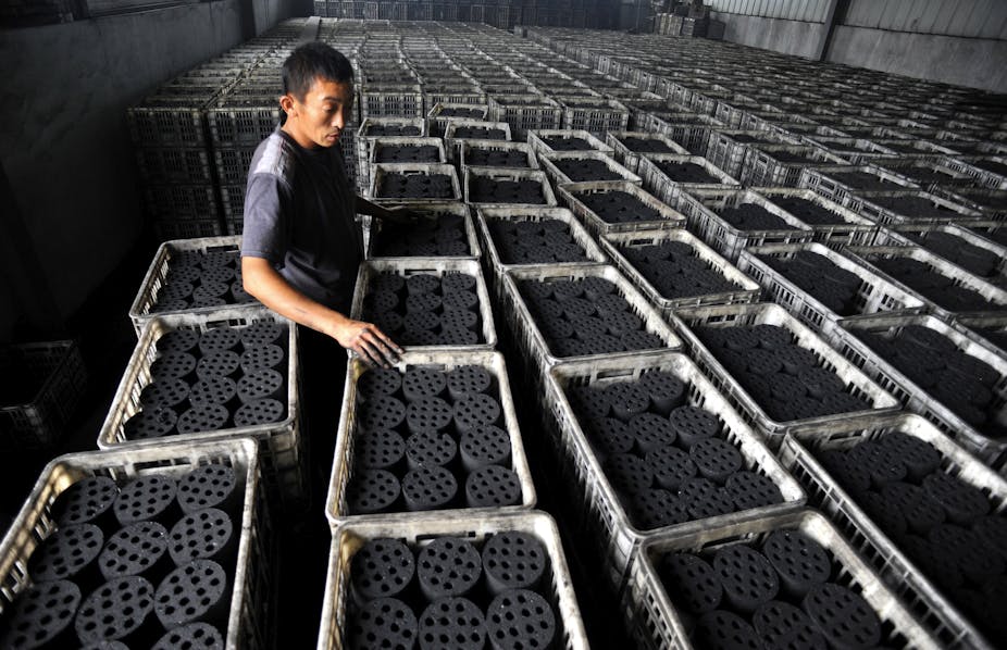 Worker overseeing checking bags of coal briquettes. 