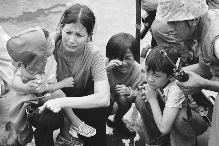 A weeping woman and her three children on a boat.