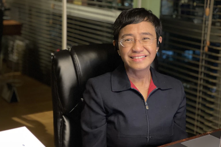 Maria Ressa sat at a desk, smiling