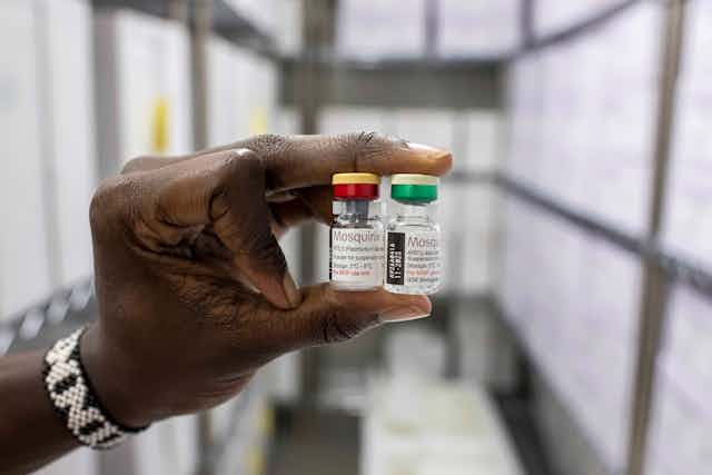A person holds two vials of the Mosquirix malaria vaccine.