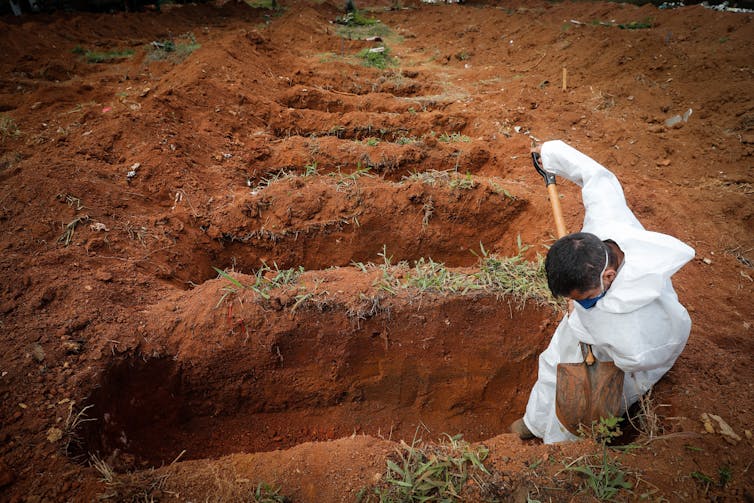 A gravedigger in Manaus, Brazil, digs a series of graves.