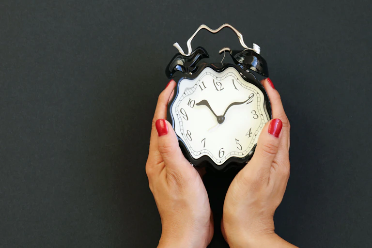 Two hands hold a blurry clock.