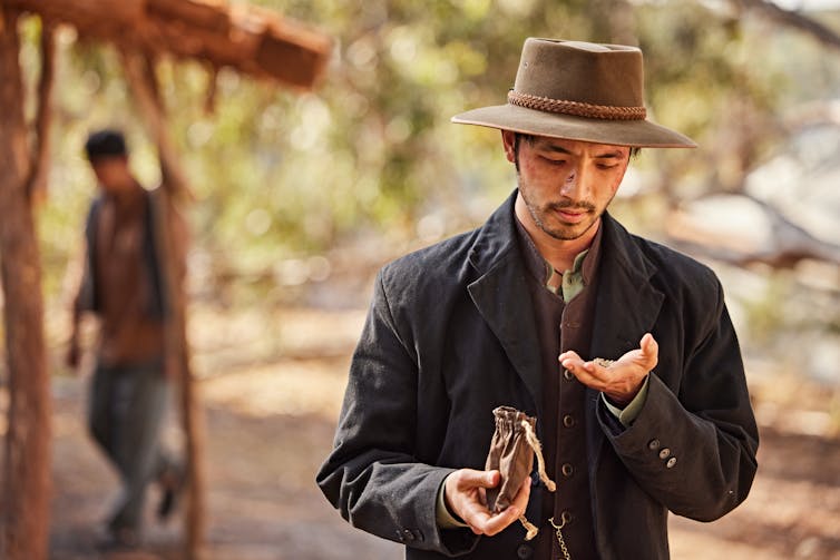 Production image: a Chinese man looks for gold in his hands.