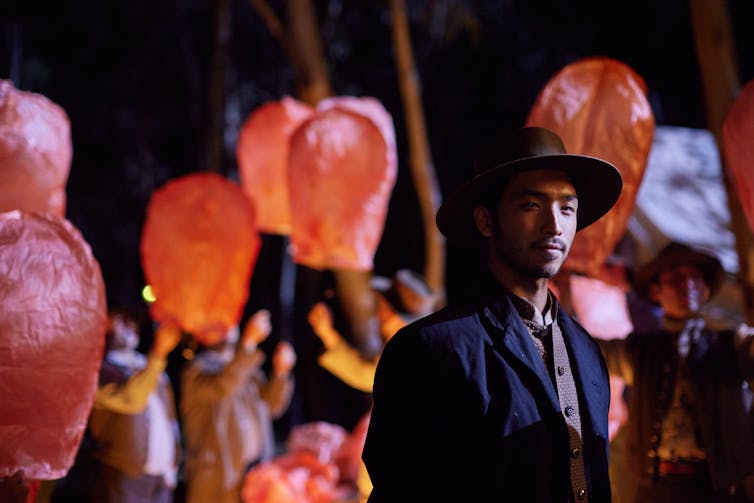 A Chinese man stands amid red lanterns