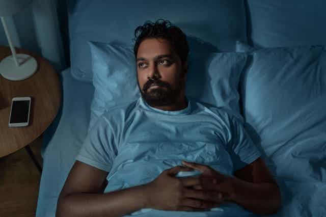 A man looks worried while lying in bed.