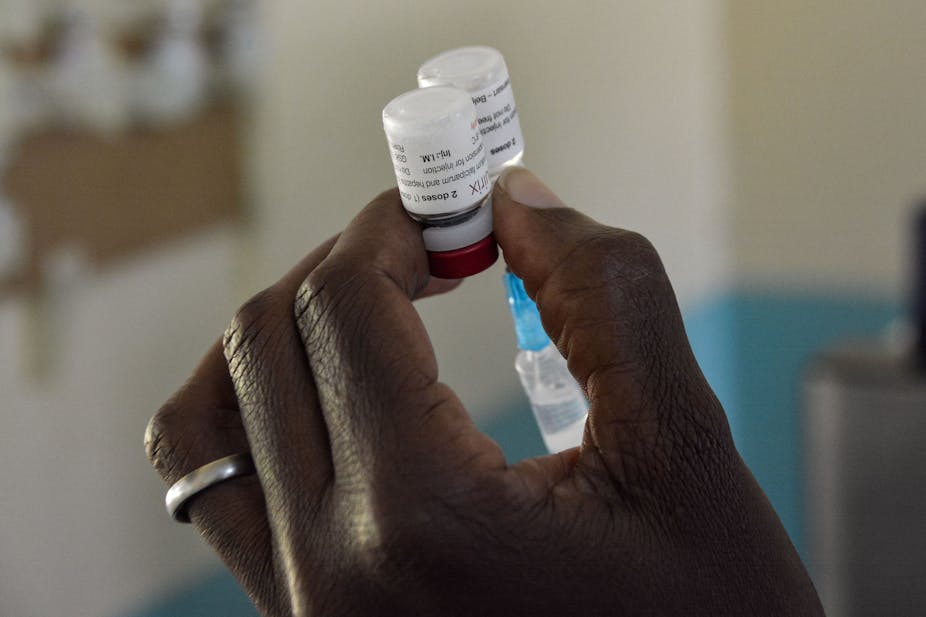 Hand holding small plastic containers and a syringe