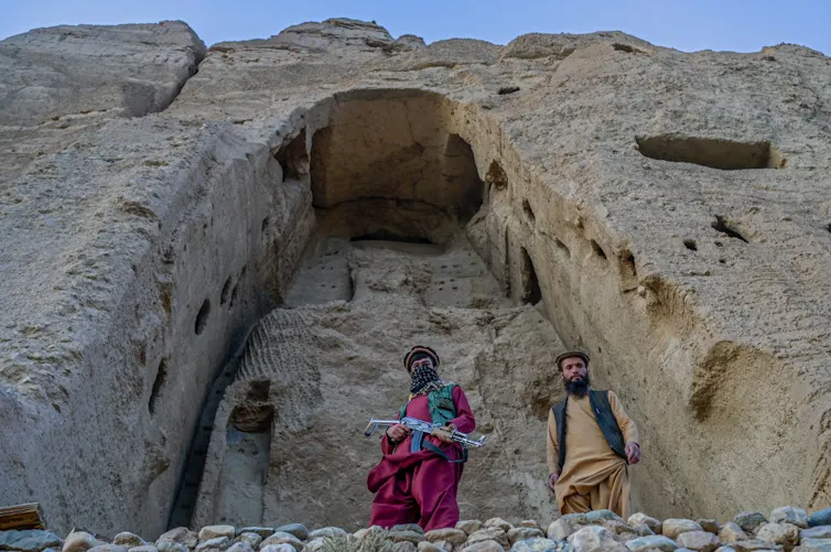 Members of Taliban stand in front of the site where the Shahmama Buddha statue once stood before it was destroyed by the Taliban in March 2001