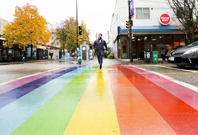 NDP leader Jagmeet Singh crosses the road at a rainbow crosswalk.