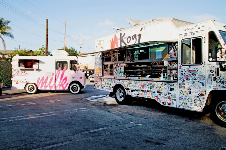 Two food trucks parked in parking lot.