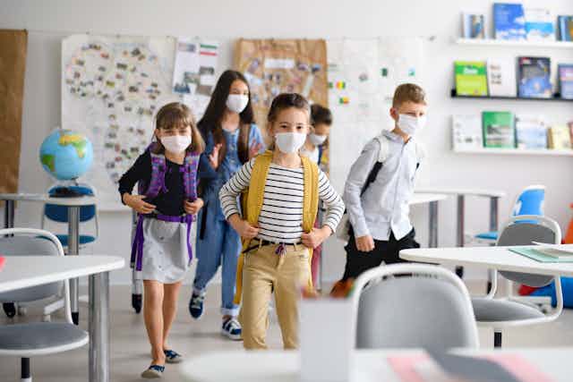 Children wearing masks enter classroom