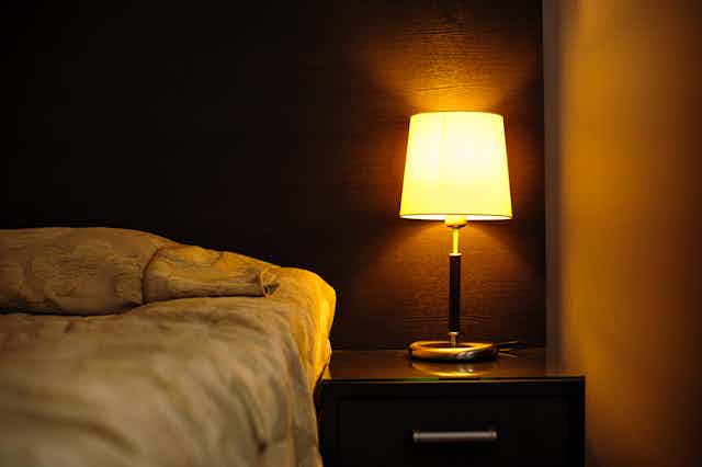 Dark bedroom illuminated by a bed-side lamp