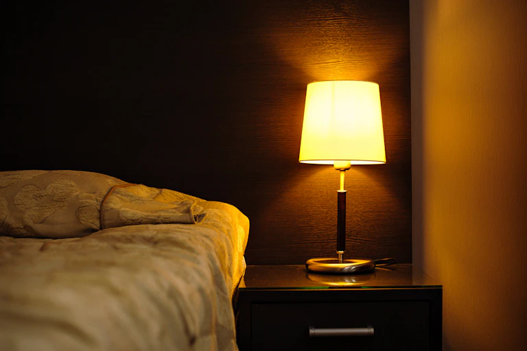 Dark bedroom illuminated by a bed-side lamp