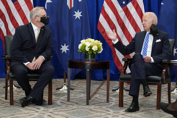 two men ion masks in front of flags