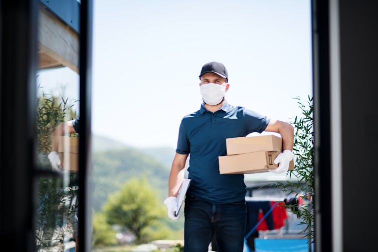 A man with a delivery box arrives at the door.