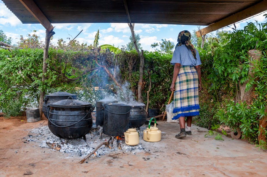 woman cooking outside with big pots