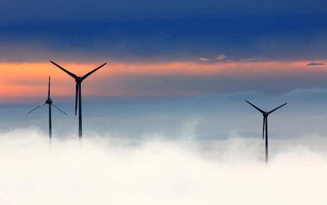 Three wind turbines above a layer of cloud