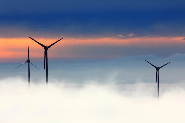 Three wind turbines above a layer of cloud
