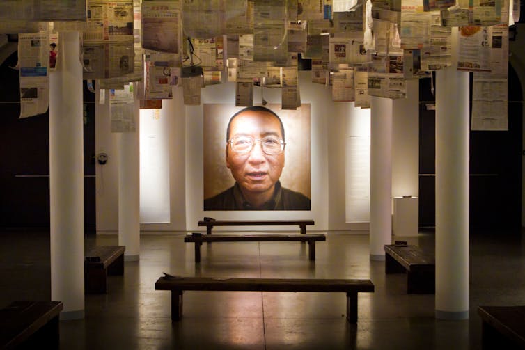 Exposición de arte utilizando periódicos alrededor de una foto de un hombre.