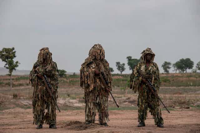 Soldiers in military fatigue, carrying rifles.