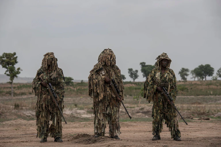 Soldiers in military fatigue, carrying rifles.