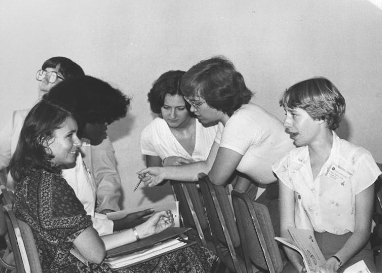 Black and white photo of six young women informally chatting while attending a conference.
