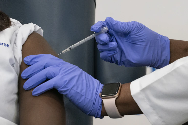 A medical worker giving a shot to a nurse.