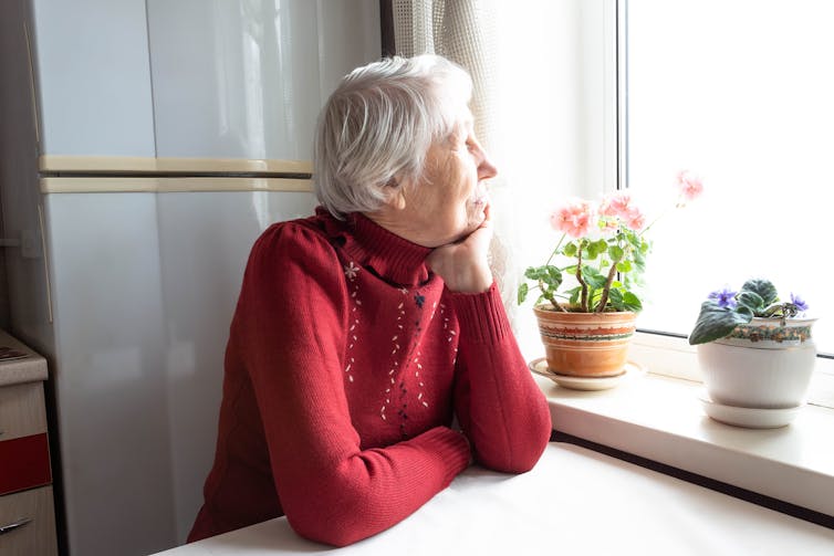 An old woman looking out of her kitchen window